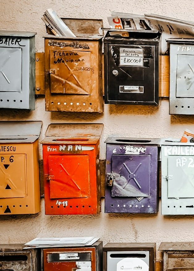 Link zum Abonnementbereich Bunte Briefkästen in verschiedenen Größen und Farben an einer Wand.